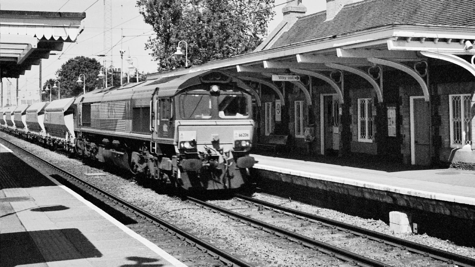 A black-and-white image of 66026 hauling a sand train through Downham Market