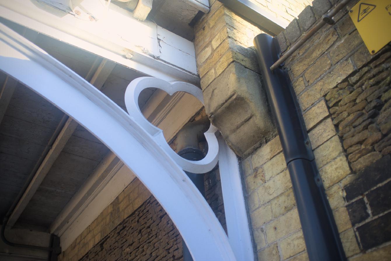 A bracket for the canopy of Downham Market&rsquo;s platform 1; it is wood painted white and has a large trefoil in the corner.