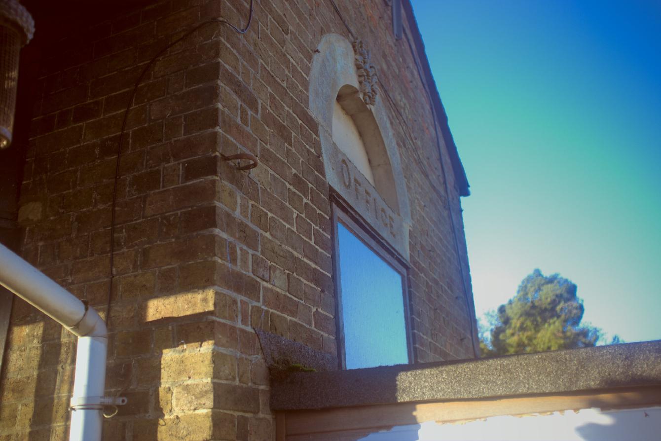 The word &ldquo;OFFICE&rdquo; engraved in a lintel above a window on the side of a brick building.