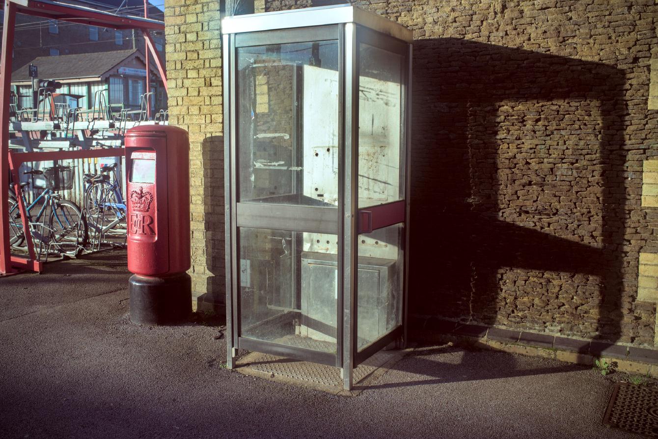 A glass phone box with its telephone clearly removed, and a red Queen Elizabeth-era post box.