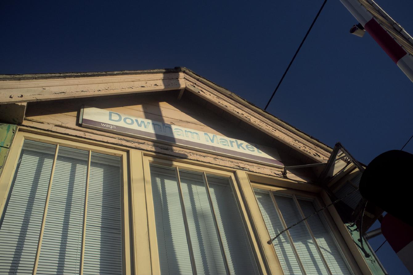 The sign on the signal box at Downham Market station. It is in the Network SouthEast style, but the bottom band has been replaced by a purple band for the WAGN operator.