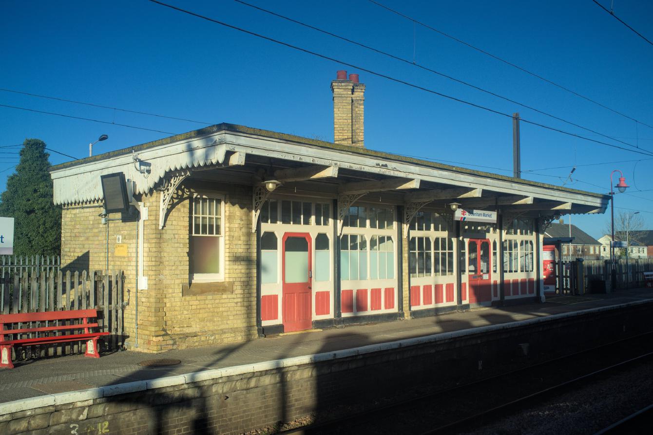 The waiting room on platform 2 at Downham Market. It is built mostly of yellow brick, with wood-and-glass paneling covering much of the platform-facing side.