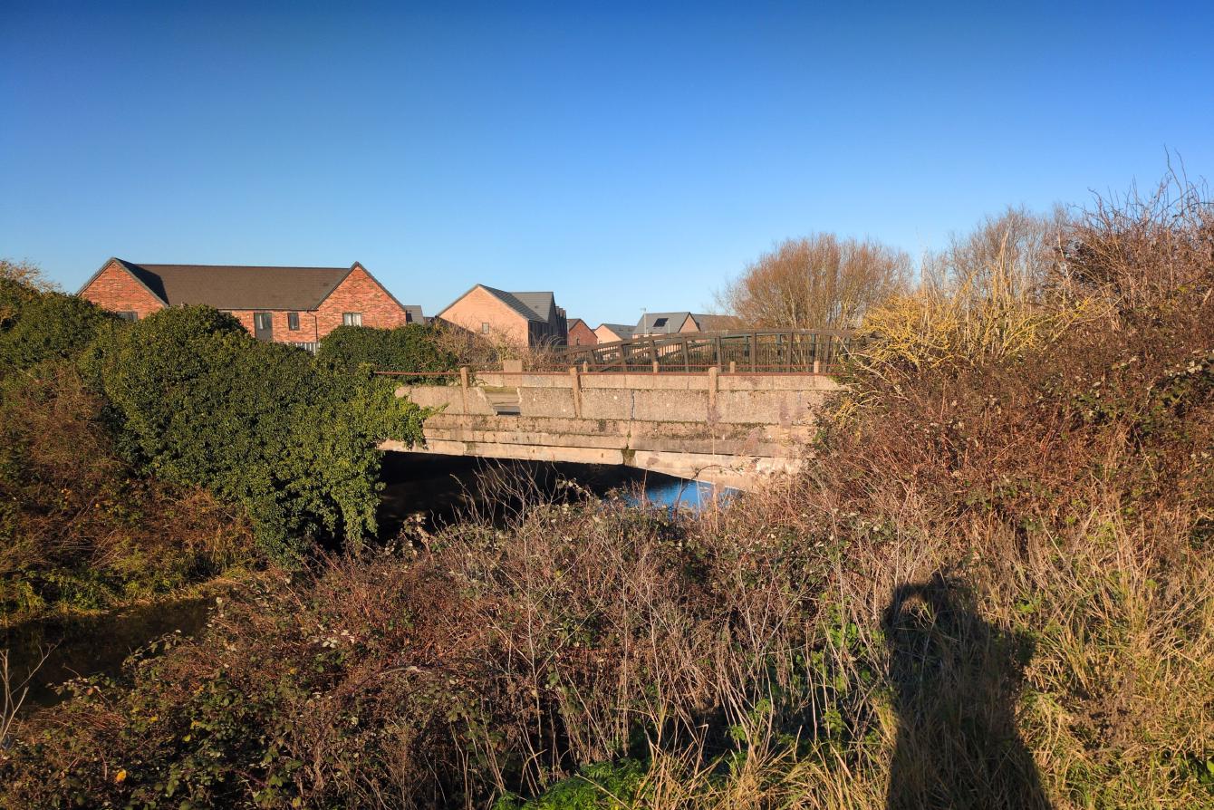 A crumbling concrete bridge over a small river.