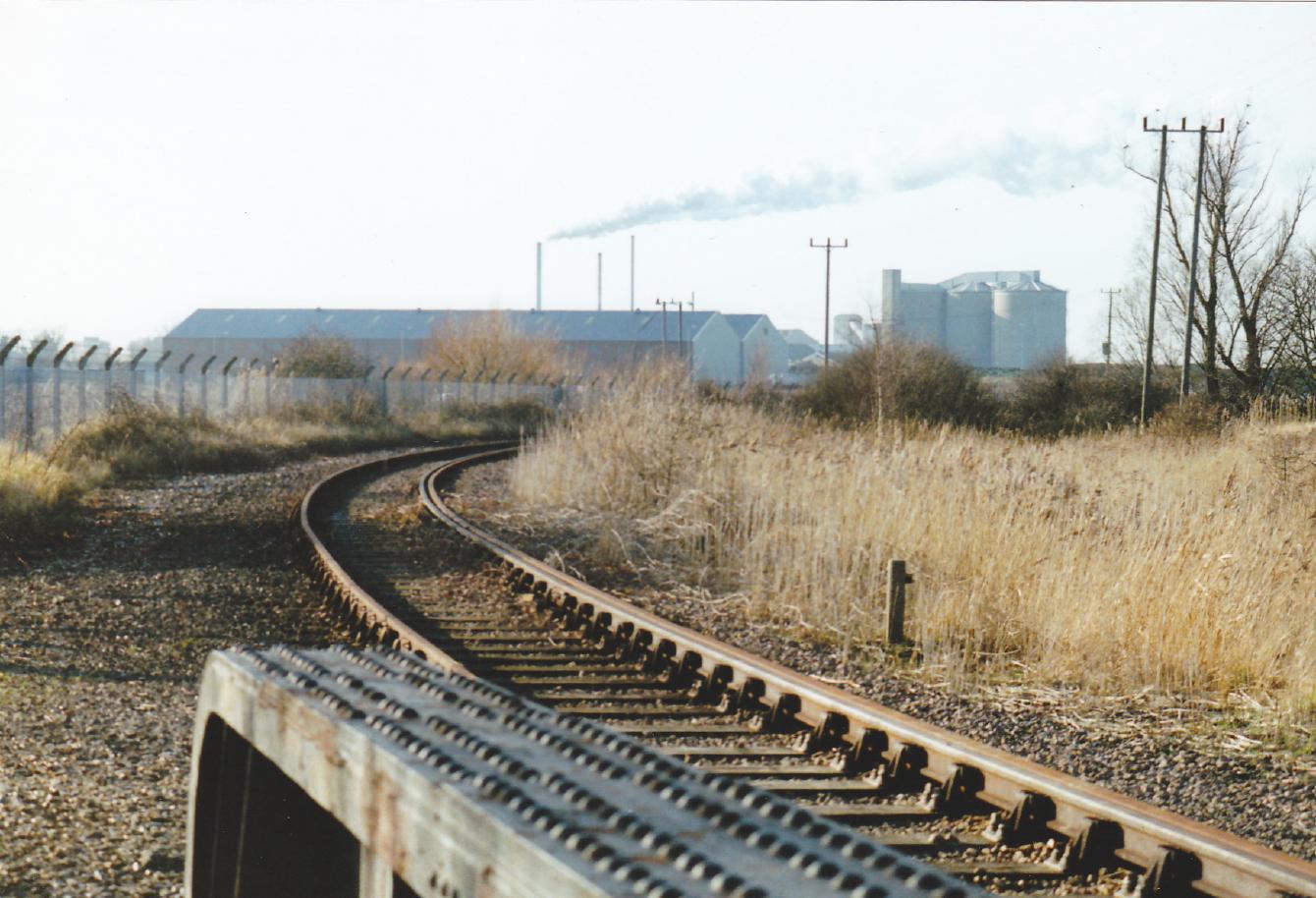 A look from the bridge towards a beet factory in the distance putting out a plume of smoke through tall chimneys