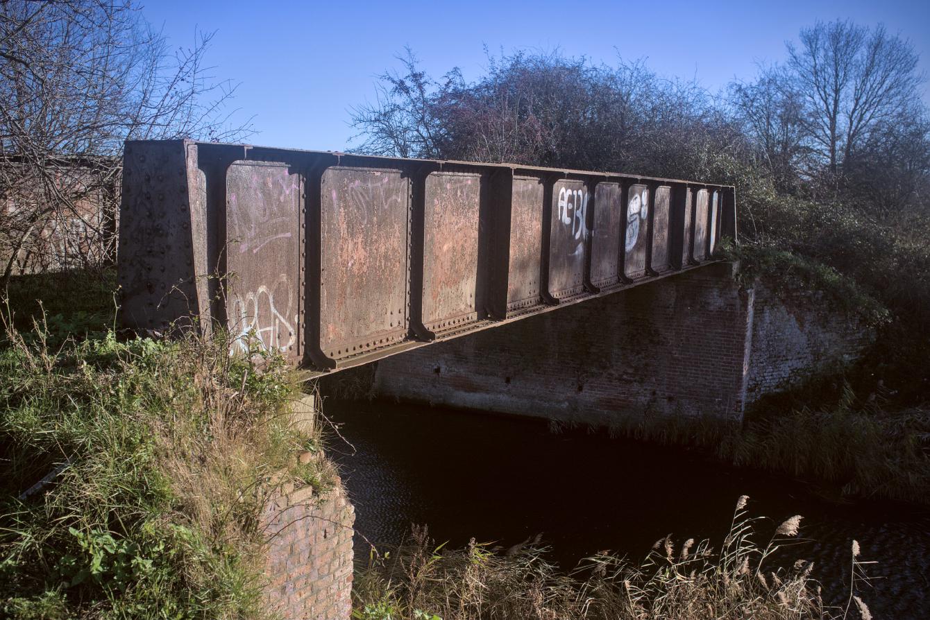 A small iron bridge over a small river. The abutments are made of brick.