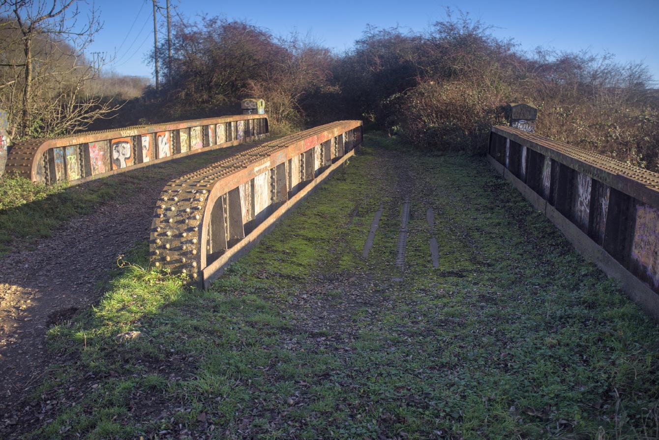 M&GN bridge 51, which is made of three iron/steel girders, one of them central, with clear evidence of track ballast either side. A little moss grows on the trackbed