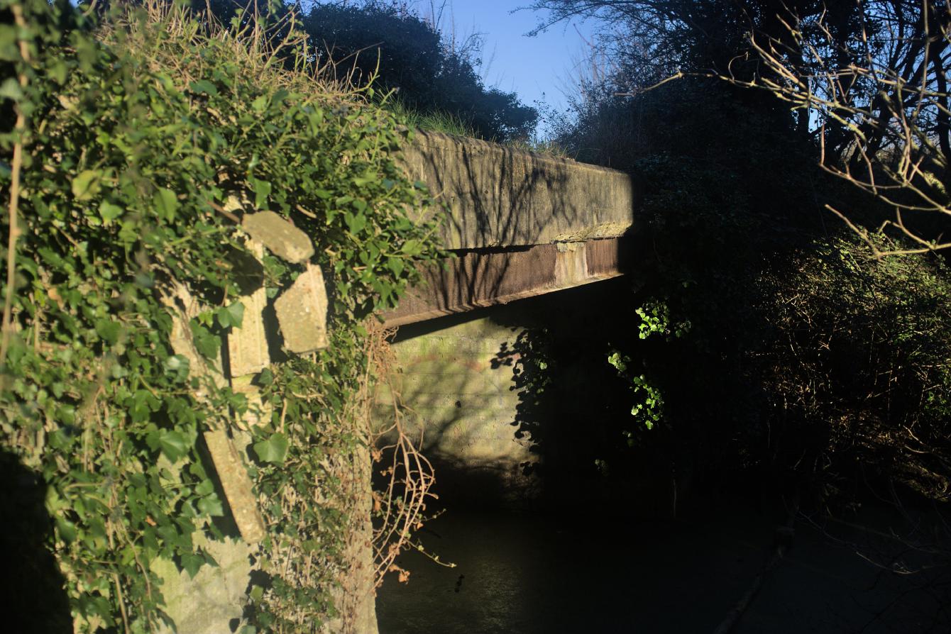 A photo of the deck of the bridge; a rusty steel deck reinforcing beam can be seen.
