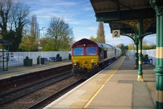 A Class 66 locomotive hauling a ballast train, passing through platform 2 at March station.