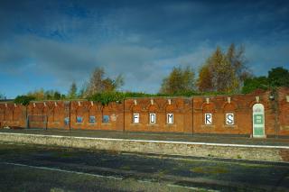 A wall on the disused part of March station. The letters FOMRS are painted on it, neatly with one for each place where a window once was. This is for Friends of March railway station.