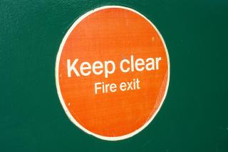 A very nearly hand-painted sign reading: Keep clear / Fire exit.