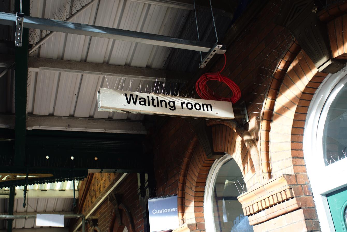 The &ldquo;Waiting room&rdquo; sign at March station. It is simple black text on a horizontal white plank.