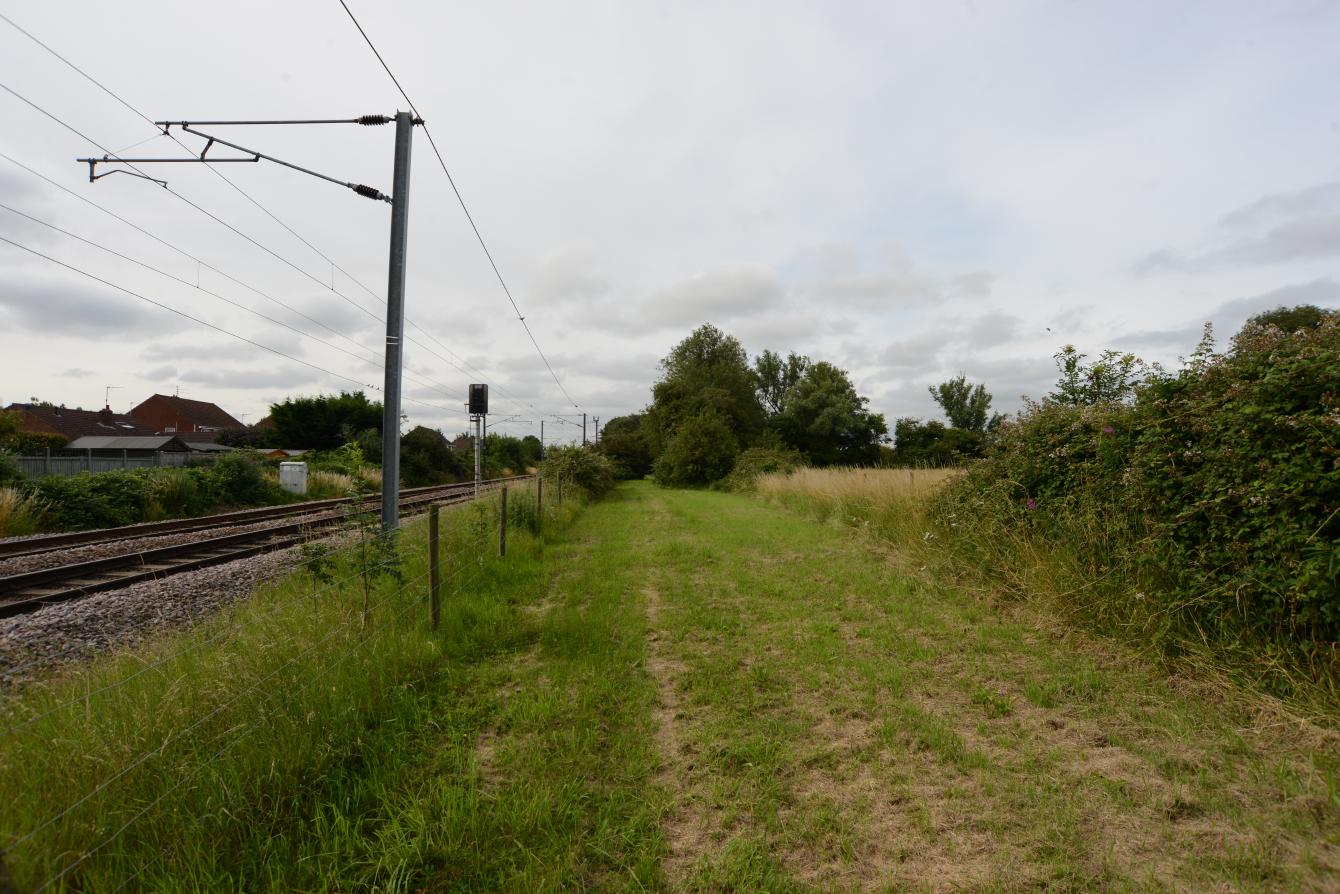 A look over a gate onto a conspicuously flat, straight area of grass.