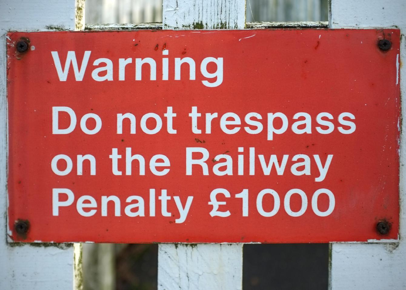 A sign with white-on-red text saying: Warning / Do not trespass on the railway / Penalty £1000