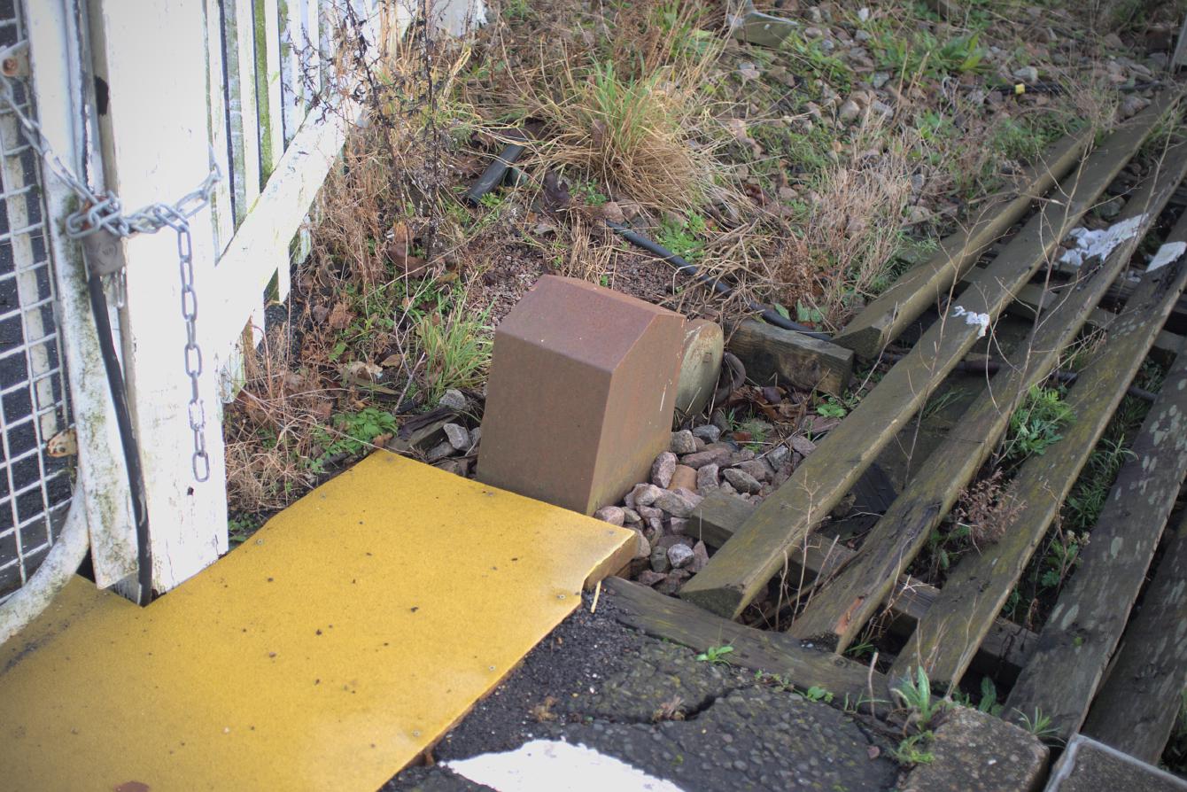 A lever with a weight at the end is linked to the white gate next to it; as the gate opens, the lever is raised, thus when the gate is released the lever drops, pulling the gate closed.