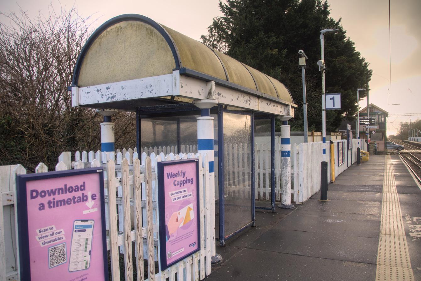 The shelter on platform 2; it has a mostly-glazed domed roof, round columns at each corner, and inside is a separately-glazed enclosed area for passengers, somewhat smaller than the overall size of the shelter.